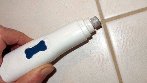 Der Dremel und ein Polieraufsatz brachte die Lösung. Danach mit Teebaumöl einreiben und es ist endlich Schluss mit dem Schimmel. Ein Dremel wird in der Hand gehalten, um Schimmel in den Fugen einer hellen Fliese zu entfernen.