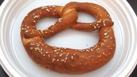 Eine Breze liegt auf einem weißen Teller, frisch geröstet und knusprig, bereit zum Genießen im gemütlichen Café.