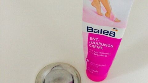 Eine Tube Enthaarungscreme steht neben einem Abfluss im Badezimmer, bereit, um verstopfte Rohre zu befreien.