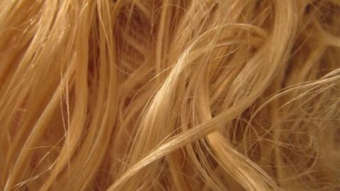 Blonde Haare schimmern im Licht, zeigen seidige, gewellte Strähnen, die nahtlos ineinander verflochten wirken.