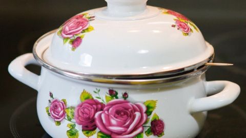 Ein weißer Topf mit Rosenmotiven steht auf dem Herd, um Überkochen mit Zahnstochern zu verhindern.