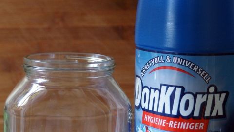 Ein Reinigungsmittel steht neben einem leeren Glasbehälter, bereit zur Anwendung, um hygienische Sauberkeit zu gewährleisten.