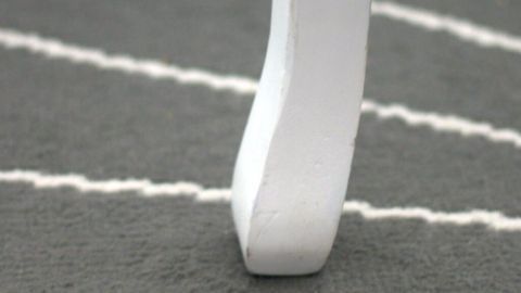 Ein weißer Tischfuß steht auf einem hellgrauen Teppich mit weißen Streifen, wo Möbelabdrücke sichtbar sind.