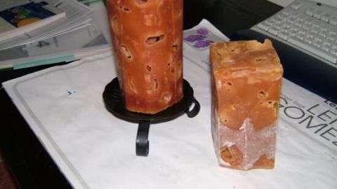 Zwei selbstgemachte Eiswürfelkerzen stehen auf einem Tisch, umgeben von Papierunterlagen und einem Computer.