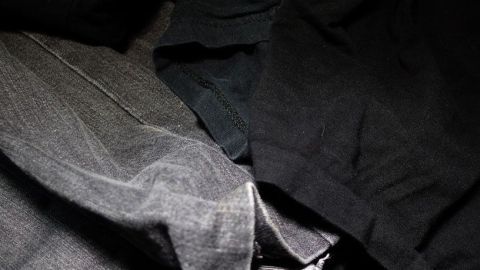 Schwarze und dunkle Wäsche auf links gedreht waschen Dunkle Wäsche liegt übereinander, während sie bereit ist, gewaschen zu werden, um Ausbleichen zu vermeiden.