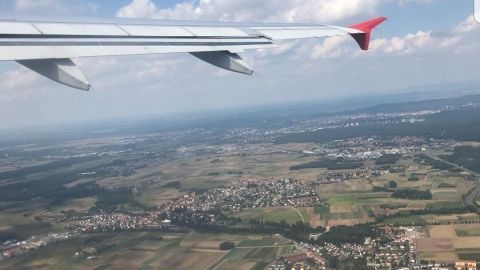 Blick aus dem Flugzeug auf eine grüne Landschaft mit Dörfern und Feldern, während man durch getrocknete Kirschen entspannt.