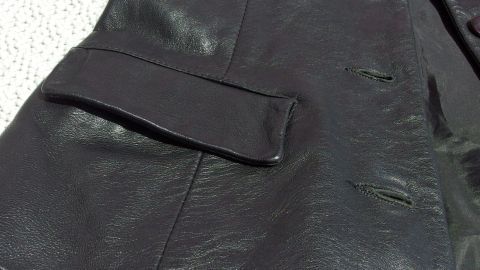 Ein schwarzes Lederstück liegt flach auf einem hellen Untergrund, bereit für die Lederpflege mit Vaseline.