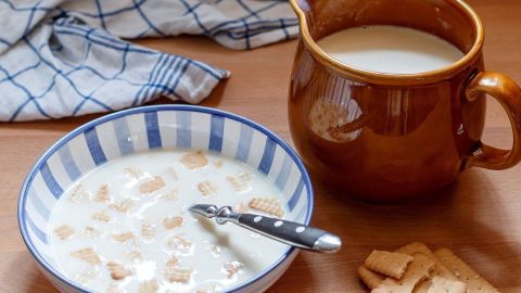 Eine Schüssel mit Koldskal steht auf einem Tisch, während ein Krug daneben Milch enthält, um das Dessert zu ergänzen.