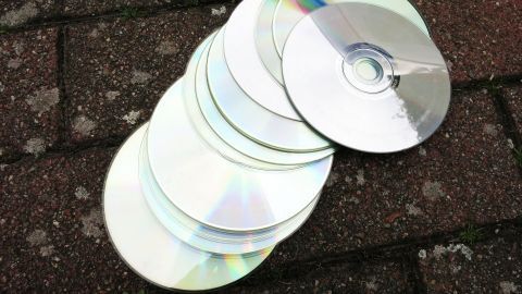 Eine Reihe alter CDs liegt auf einem grauen Untergrund, bereit, um für ein kreatives Spiel verwendet zu werden.