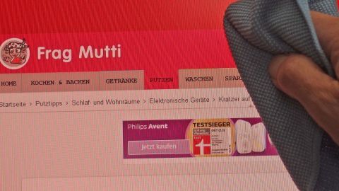 Ein Hand wischte mit einem Tuch über einen Computerbildschirm, auf dem "Kratzer auf Bildschirm" steht.