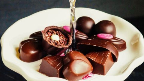 Ein silberner Keksständer hält eine Auswahl an Lindt-Schokolade, schön angerichtet auf einem weißen Teller.