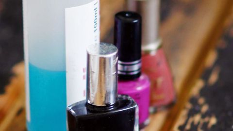 Eine verklebte Nagellackflasche steht neben einem Lösungsanbieter auf einem Holzuntergrund und wartet auf das Öffnen.