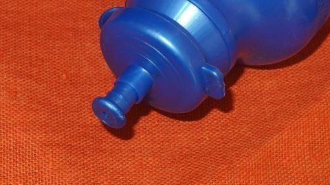 Eine blaue Flasche steht auf einem orangefarbenen Untergrund, bereit zur Anwendung als günstige Alternative zur Nasendusche.