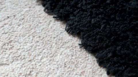 Entferne hartnäckige Flecken wie Window Color, Knete und Kaugummi aus Teppichen mühelos. Mit ein paar einfachen Tricks wird jeder Teppich wieder sauber und gepflegt, egal ob heller oder dunkler Flor. Eine schwarze Teppichkante stößt auf einen beige Teppich, deutlich unterschiedliche Strukturen, nebeneinanderliegend.