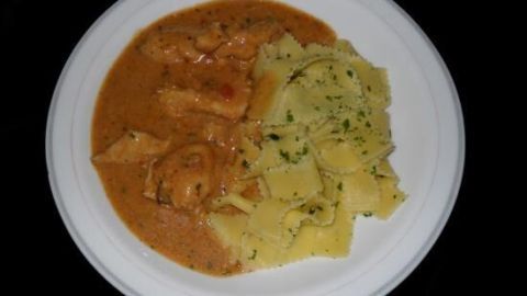 Auf einem weißen Teller liegt Hähnchengeschnetzeltes in einer würzigen Sauce, begleitet von Kartoffeln und Kräutern.