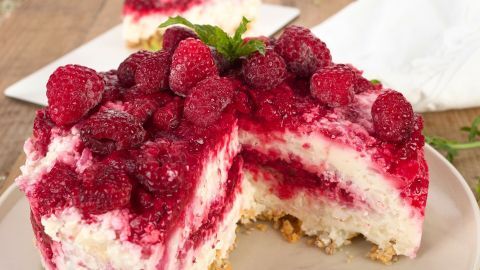 Eine köstliche Milchreistorte mit Himbeeren und Sahne ist auf einem Teller angerichtet und lädt zum Genießen ein.