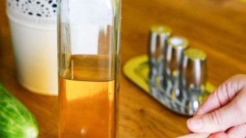 Ein Glas Honig wird mit einem Holzlöffel aus einer Glaskaraffe entnommen, um ein Honig-Senf-Dressing zuzubereiten.