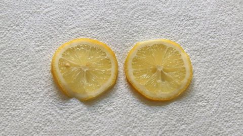 Zwei geschnittene Zitronenscheiben liegen auf einem Küchenpapier, bereit für einen Wickel bei Halsschmerzen.