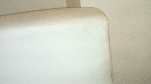 Eine helle Ledercouch mit einem kleinen Fleck an der Ecke, die darauf hinweist, dass Schmutzradierer zur Reinigung eingesetzt werden könnten.