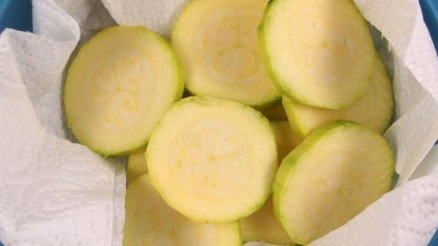 Scheiben von frischem Gemüse liegen auf Küchenpapier in einem Behälter, bereit zur Aufbewahrung für eine längere Frische.