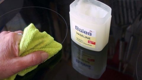 Glaskeramikfeld mit Vaseline einreiben bringt schönen Glanz und macht es unempfindlicher gegen Kratzer. Ein Handtuch reinigt ein glänzendes Glaskeramikfeld, während eine Vaseline-Dose daneben steht.