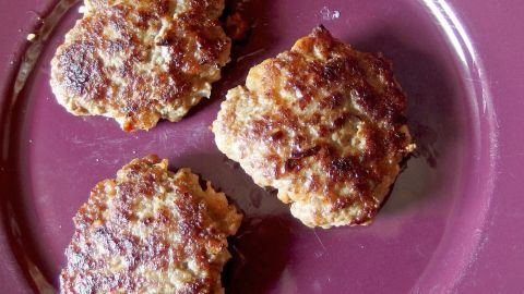 Mit der Zugabe von Haferflocken in den Hackfleischteig erhält man die besten, lockersten Frikadellen! Drei besonders lockere Frikadellen liegen auf einem dunklen Teller, goldbraun gebraten und appetitlich angerichtet.