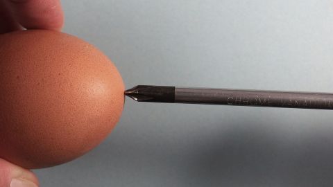 Ein Hand hält ein Ei, während ein Werkzeug dafür verwendet wird, um ein (Oster)-Ei auszublasen.