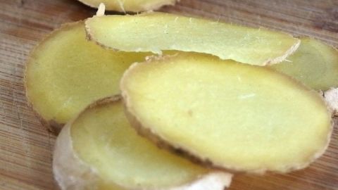 Frische Ingwerscheiben liegen auf einem Holzbrett, bereit zur Verwendung gegen Halsschmerzen und Halsentzündung.