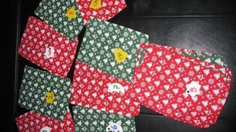 Bunte Adventssäckchen in Rot und Grün liegen auf einem Tisch, dekoriert mit kleinen Aufnähern, bereit zum Befüllen.