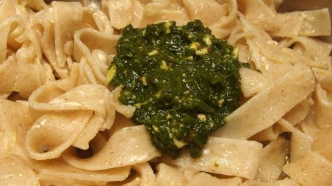 Hausgemachte Nudeln liegen in einer Schüssel, darauf ein Klecks frisches Pesto, einfach und schnell zubereitet.