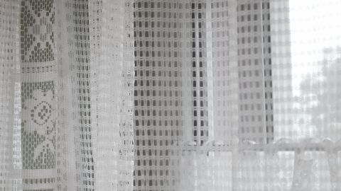 Kein Durcheinander mit den Röllchen beim Waschen von Gardinen: Gardinen im Kopfkissenbezug waschen. Helle Gardinen hängen vor einem Fenster und lassen sanft Licht herein, während sie sauber und frisch aussehen.