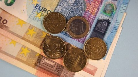 Münzen und Geldscheine liegen auf einem Tisch, symbolisieren Sparen und mögliche Gewinne im finanziellen Kontext.