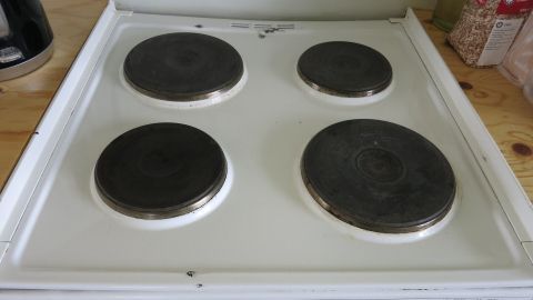 Herdplatten glänzen in Schwarz, während sie auf einem weißen Herd montiert sind, umgeben von einer neutralen Holzoberfläche.
