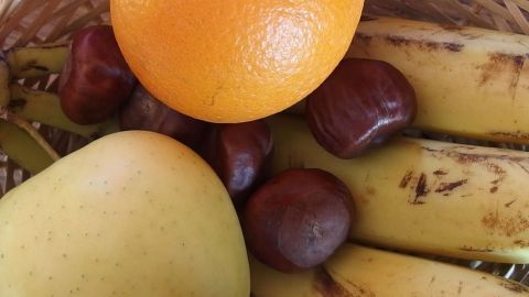 In einem Korb liegen Banane, Apfel, Kastanien und eine Orange, was eine natürliche Grundlage gegen Obst-/Fruchtfliegen bildet.