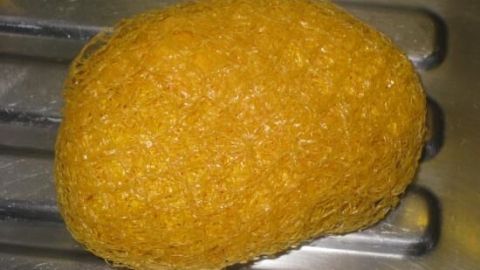 Ein leeres Obstnetz ist über eine Kartoffel gespannt, liegt in einer Edelstahlspüle.