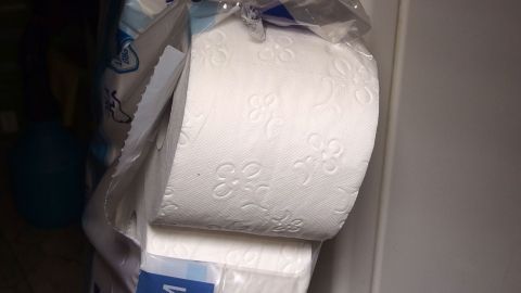 Ein Stapel weißer Papiertücher liegt auf einem Regal, bereit zur Verwendung in kleinen Badmülleimern.