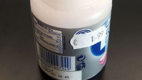 Eine Verpackung mit einem Preisaufkleber, der 1,99 Euro anzeigt, steht auf einer dunklen Fläche, um Preise zu vergleichen.
