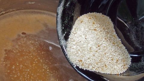 Ein Stück Brot wird über einer Brühe gehalten, um als Soßenbinder zu dienen und die Flüssigkeit zu verdicken.