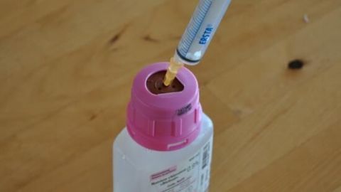Eine Nasensaugerflasche steht auf einem Holztisch, mit einer Spritze, die bereit ist, um Verstopfte Nase bei Babys zu behandeln.