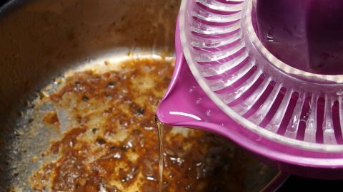 Edelstahltopf mit angebrannten Resten wird mit einem Zitronensaft-Squeezer gereinigt, um Rückstände zu entfernen.