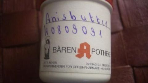 Ein weißes Gefäß mit rotem Deckel zeigt die Aufschrift "Anisbutter H0809091" und das Logo der "Bären Apotheke".
