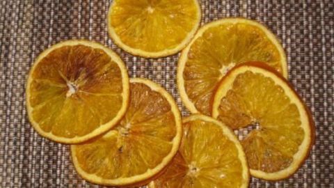 Dünne, getrocknete Orangenscheiben liegen auf einem gewebten Tisch. Ideal für die Weihnachtsbastelei und Dekoration.