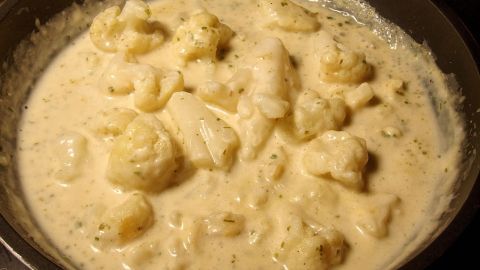 Eine cremige Soße mit Klümpchen in einer Pfanne, während sie sanft erhitzt wird, um eine perfekte Konsistenz zu erreichen.