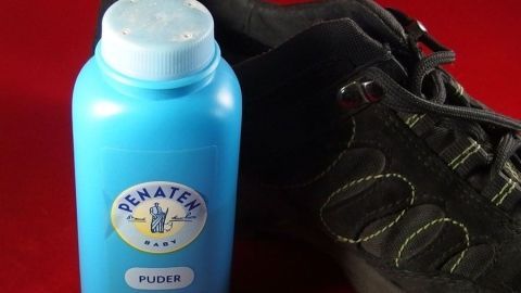 Ein blauer Puderbehälter steht neben einem Schuh, um quietschenden Schuhen in einem roten Umfeld Abhilfe zu schaffen.