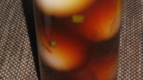 Im Glas sind mehrere eingelegte Eier zu sehen, die in einer dunklen Essig-Kräuter-Lösung schwimmen.