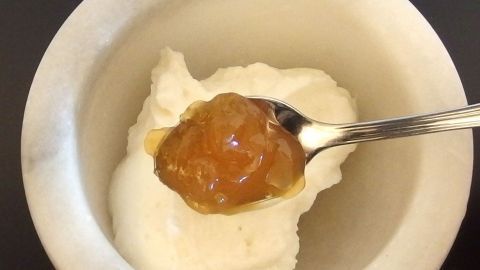 Fruchtquark wird mit einem Löffel Marmelade in einer Schüssel serviert, um eine kreative Variante zu zeigen.