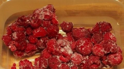 Gefrorene Himbeeren liegen in einer Schüssel, bereit, im Mixer zu Eis verarbeitet zu werden.