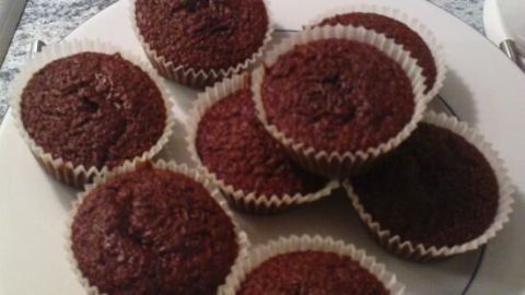 Schokomuffins liegen auf einem weißen Teller in einer Küche, umgeben von grauer Marmorarbeitsplatte und weißen Fliesen.