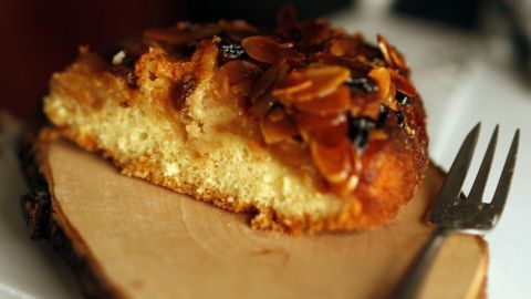 Ein leckeres Stück Apfel-Krümel Kuchen liegt auf einem Holzbrett, umgeben von einer gemütlichen Küchenumgebung.