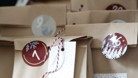 Kleine, braune Päckchen liegen auf einem Tisch, nummeriert und dekoriert, bereit für einen Adventskalender für Blumenfreunde.